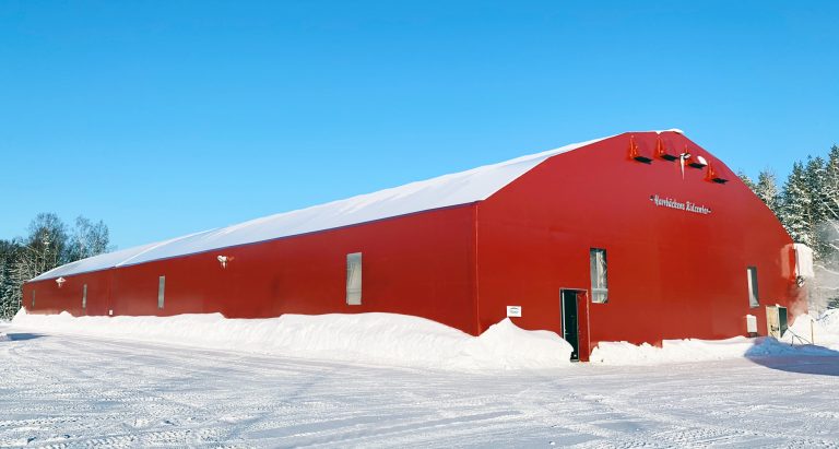 Snötäckt ridhall med röda fasader