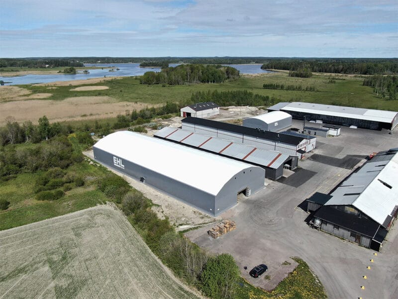 Gråa industritält hos EHL Prolist. Blå himmel och sjö i bakgrunden. Bild tagen med drönare på anläggningen i Möklinta